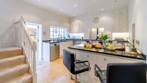A modern kitchen with a central island, white cabinetry, and a stainless steel dishwasher.