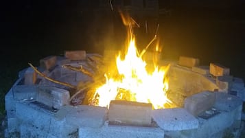 A campfire in a circular stone fire pit surrounded by grass.