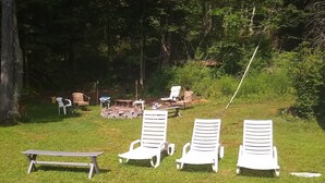 A grassy outdoor area with several white lounge chairs and a picnic table.