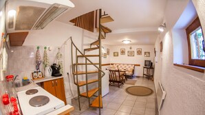 A compact kitchen with a built-in stove, a sink, and a spiral staircase leading to the upper floor. - Apartment Azur (Budva)