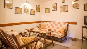 A cozy living room with a sofa, chairs, a table, and framed artwork on the walls. - Apartment Azur (Budva)