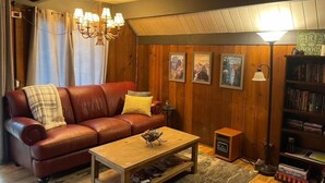 A cozy living room with a leather sofa, a wooden coffee table, and a bookshelf.