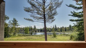 A wooden deck with a view of a lake surrounded by trees. - Privat Hot Tub! Sleeps 6 *Traverse City *Sleeping Bear Dunes (Interlochen)