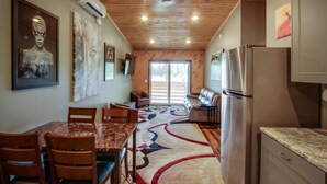 A modern kitchen with a wooden ceiling, stainless steel appliances, and a dining area with a marble table and chairs. - Privat Hot Tub! Sleeps 6 *Traverse City *Sleeping Bear Dunes (Interlochen)