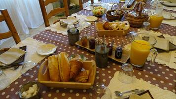 Mesa de café da manhã posta com pão, doces e bebidas.