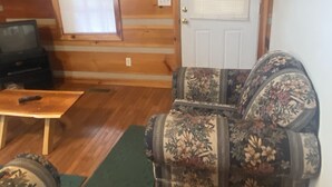 A log cabin interior with a wooden floor, a sofa, a coffee table, and a television. - Beautiful Cabin Nestled in the Smokies (Hartford)