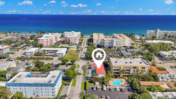 Vista aérea de un pueblo costero con un hotel destacado, marcado por un icono de ubicación.