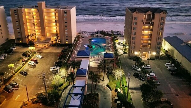 Un hotel con varias edificaciones, piscina y vista al mar.