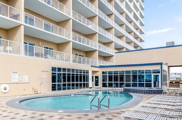 A hotel with a pool area, multiple balconies, and a building facade with large windows.