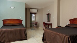 A hotel room with two beds, a desk, a chair, a mirror, and an air conditioning unit. - Hotel San Juan (Villahermosa)