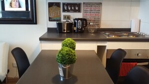 A modern kitchen with a coffee machine, kettle, and a motivational poster on the wall. - A2 lindo y comodo 2D 2 B full equipado hasta 6 pax metro en la puerta (Santiago)