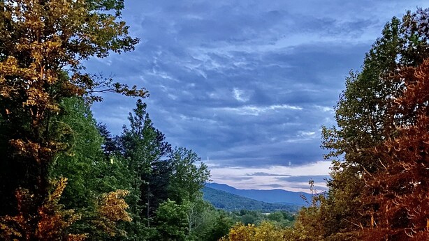 A deck with a round metal table and chairs, surrounded by trees and a view of distant mountains under a cloudy sky. - Secluded Cabin w/ HOT TUB, Woodburning Stove, VIEW on PRIVATE 2 acres (Cosby)