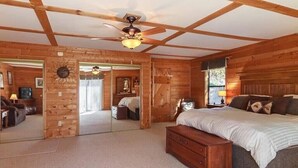 A wooden cabin bedroom with a large bed, a ceiling fan, and a mirror. - Secluded Cabin w/ HOT TUB, Woodburning Stove, VIEW on PRIVATE 2 acres (Cosby)