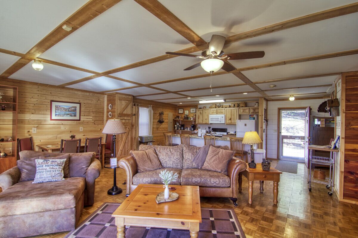 Interior de una cabaña de troncos con sala de estar, cocina y comedor.