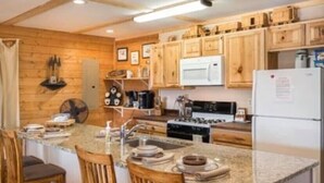 A kitchen with wooden cabinets, a granite countertop, a stove, a sink, and bar stools. - Secluded Cabin w/ HOT TUB, Woodburning Stove, VIEW on PRIVATE 2 acres (Cosby)