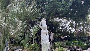 A garden with a statue, a fountain, and potted plants. - The Law Building (Natchez)