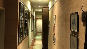 A hallway with wooden walls, a patterned rug, and framed pictures on the right. - The Law Building (Natchez)
