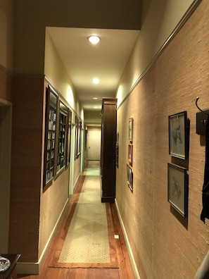 Stunning hallway with framed artwork and a bookshelf, leading to a door.