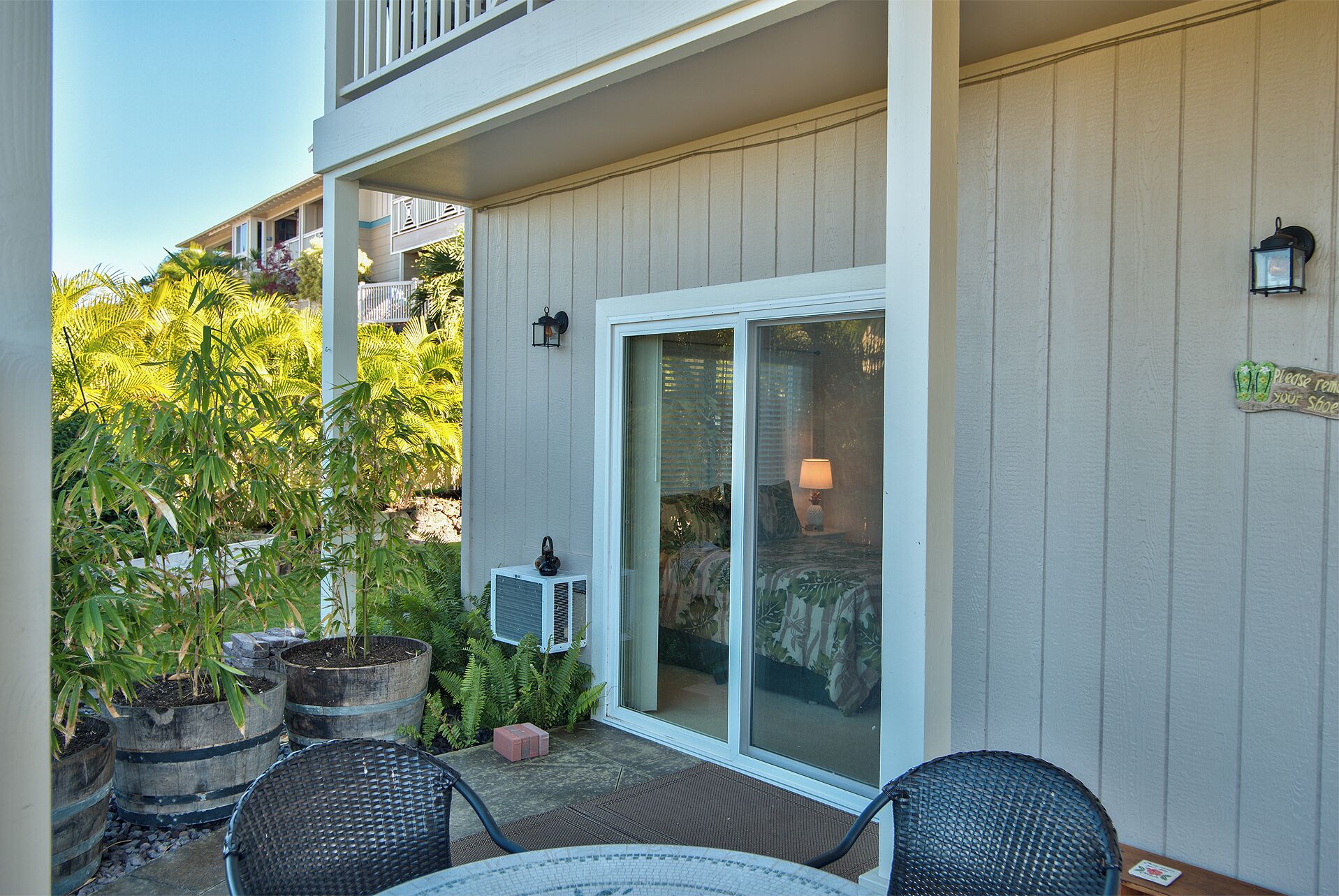 A patio with a sliding glass door, outdoor furniture, and potted plants.
