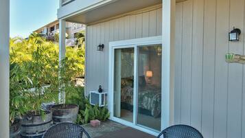 A patio with a sliding glass door, outdoor furniture, and potted plants.