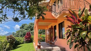Une maison avec un balcon, un jardin et une vue sur les montagnes.