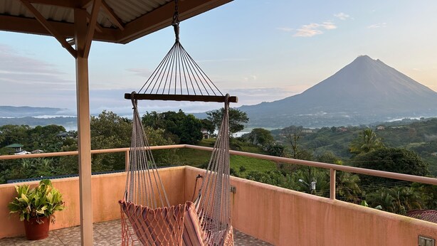 Un fauteuil suspendu sur un balcon avec vue sur une montagne.