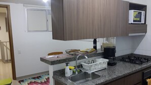 A compact kitchen with a granite countertop, a built-in sink, a microwave, and a stove.