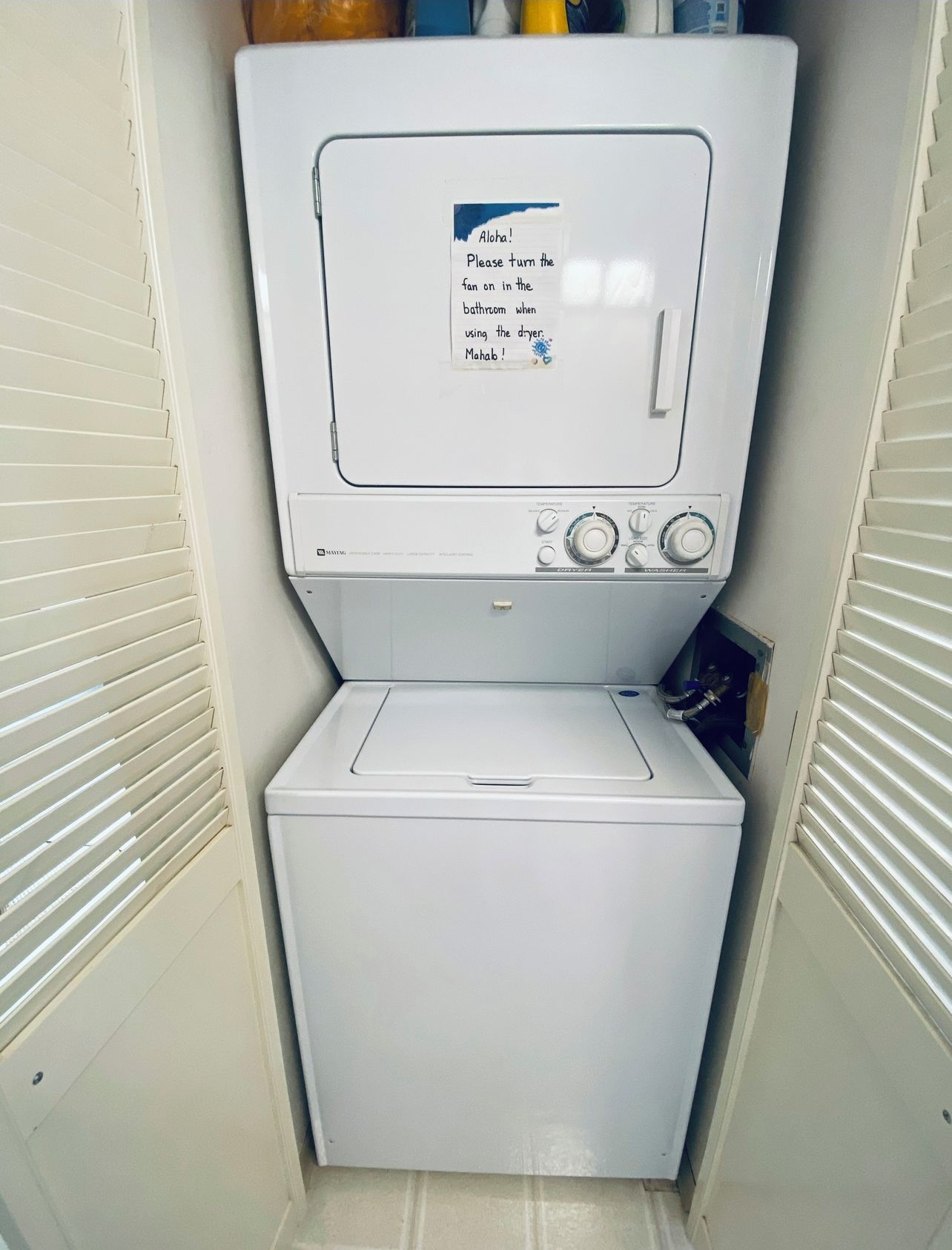 Een compacte, witte wasmachine met een bedieningspaneel en een briefje aan de voorkant.