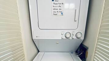 Een compacte, witte wasmachine met een bedieningspaneel en een briefje aan de voorkant.