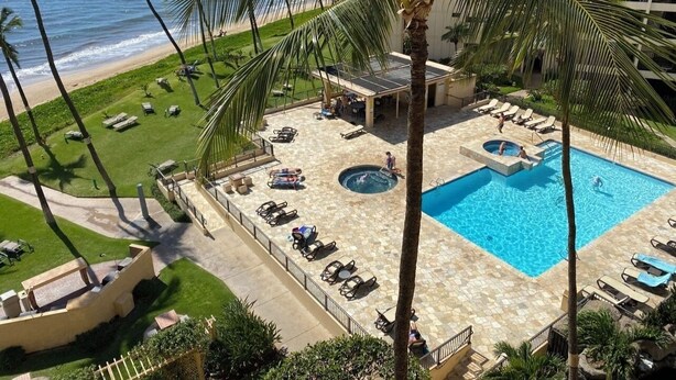 A resort pool area with lounge chairs, a hot tub, and a view of the ocean. - Spectacular Summer Specials - Beachfront Condo With Amazing Oceanfront Views. (Kihei)