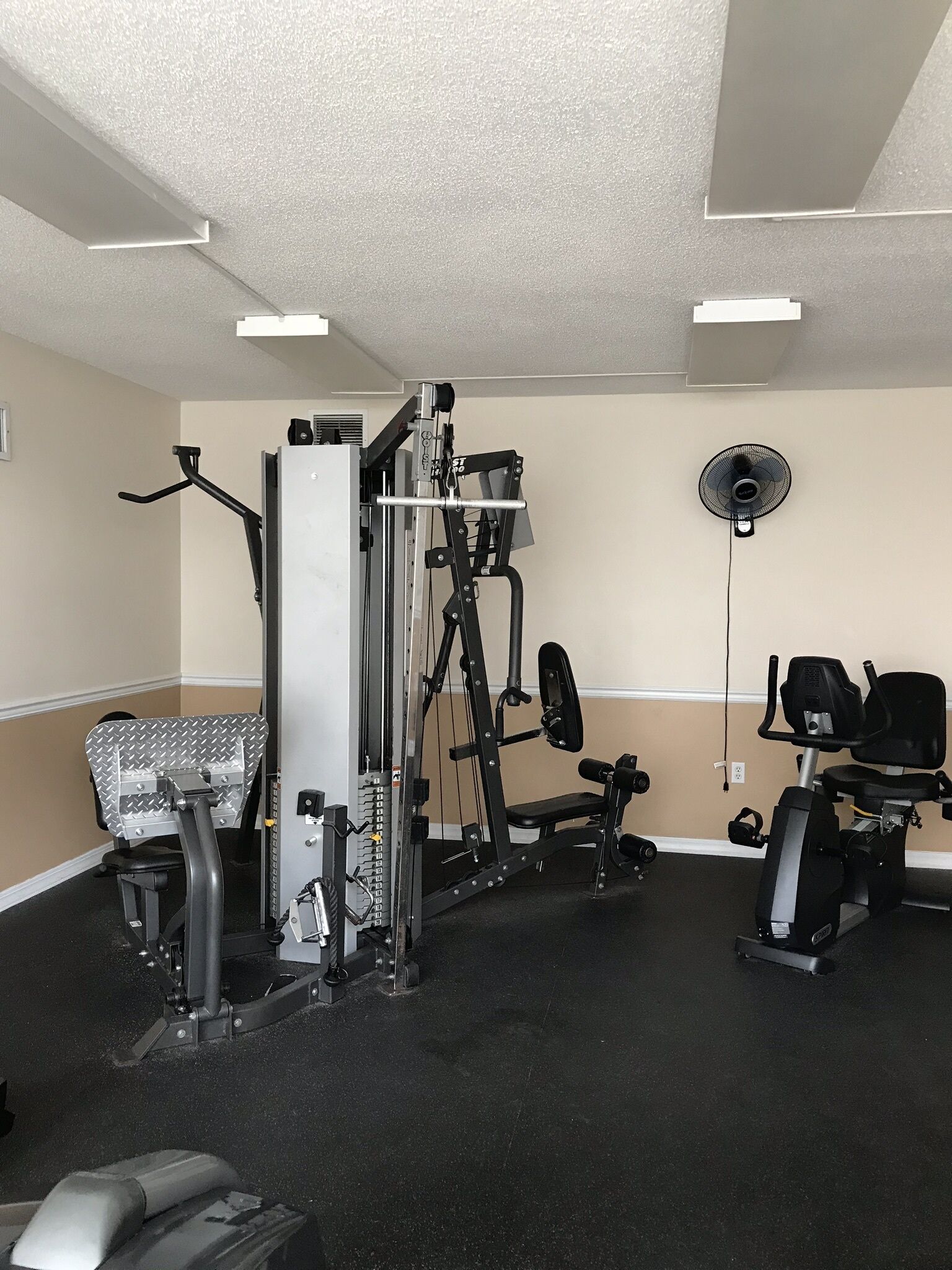 A gym with a variety of exercise equipment including a weight bench, a stationary bike, and a multi-functional workout machine.