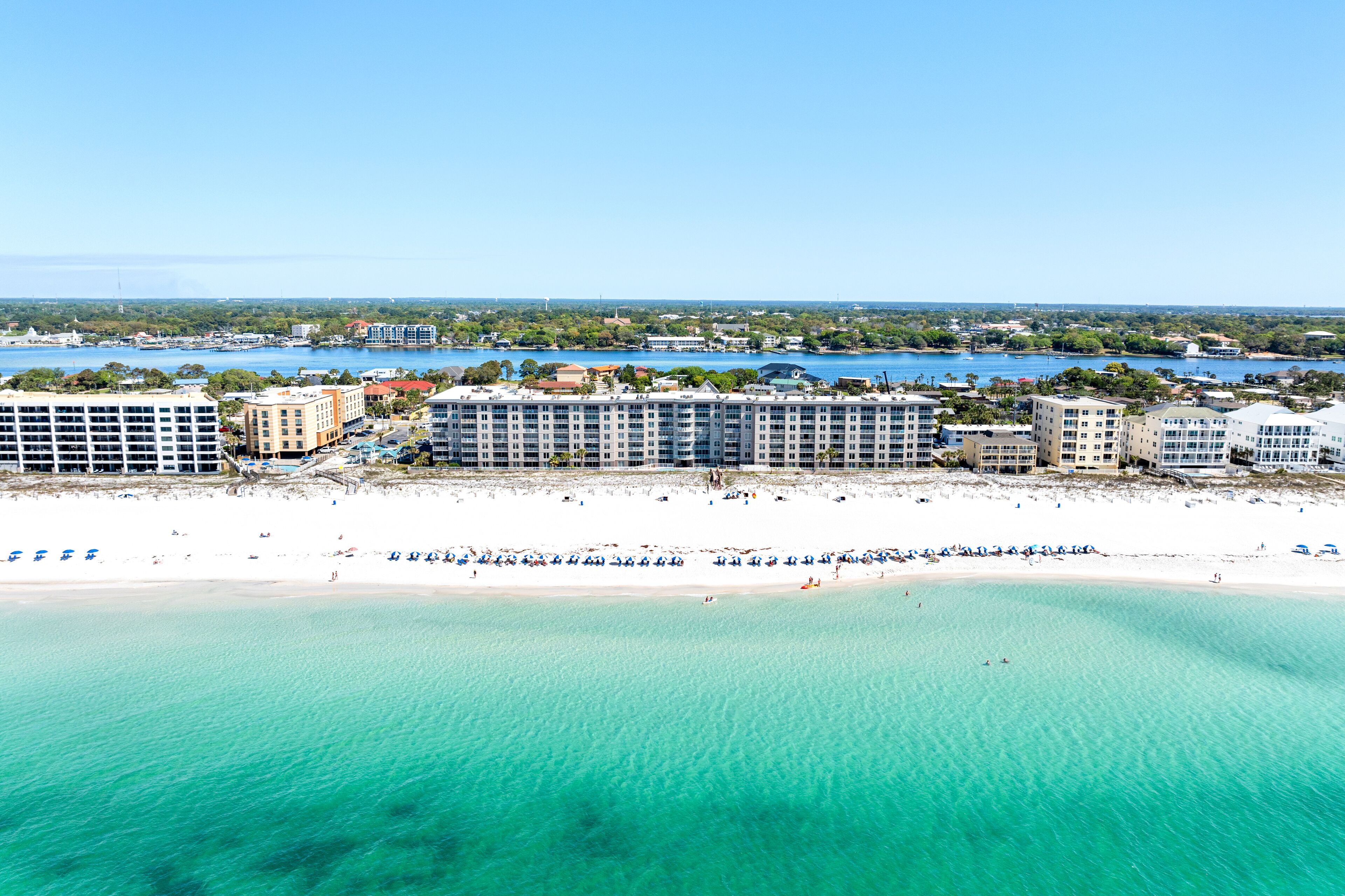 Un hotel frente al mar con varias construcciones, una playa y un puerto deportivo.