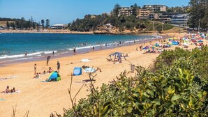 A beach with people sunbathing and swimming, tents, and umbrellas. - 1 Hour from Sydney 500 meters to Terrigal beach, restaurants and night life. (Terrigal)