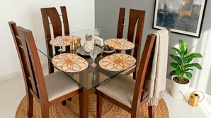 Un tavolo da pranzo con quattro sedie, un piano in vetro e piatti decorativi.