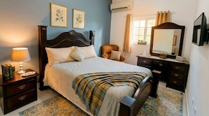 A bedroom with a bed, bedside table, lamp, dresser, mirror, and framed botanical prints on the wall. - Luxury Near Beach Apartment w/ Free Netflix & WiFi (Puerto Plata)