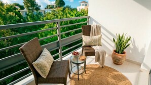 Un balcone con mobili in vimini, un tavolino con una ciotola di frutta e una pianta in vaso.