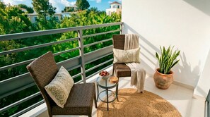 A balcony with wicker furniture, a small table with a bowl of fruit, and a potted plant. - Luxury Near Beach Apartment w/ Free Netflix & WiFi (Puerto Plata)