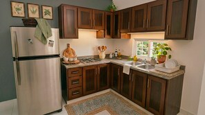 Una cocina con gabinetes de madera oscura, un refrigerador de acero inoxidable y una ventana con vista a follaje.