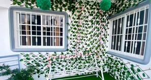 A room with two windows, a white lattice wall, and green foliage.