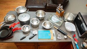 Un plan de travail de cuisine avec divers ustensiles de cuisine, des casseroles, des poêles et un four à micro-ondes.