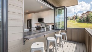 Una cucina moderna con mobili bianchi, elettrodomestici in acciaio inossidabile e un'ampia finestra con vista su un paesaggio verde.
