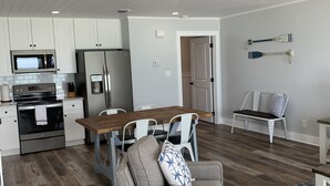 Une cuisine moderne avec des meubles blancs, des appareils en acier inoxydable et une table à manger en bois.