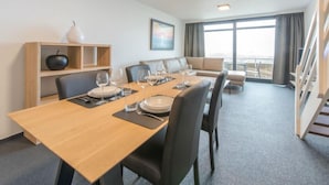 Ein modernes Hotelzimmer mit Essbereich, einer Couch und einer Treppe.