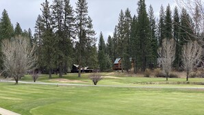 Ein Golfplatz mit gepflegtem Grün, einem Fußweg und einem Jagdhaus im Hintergrund.