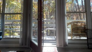 Ein Zimmer mit großen Fenstern, einer Holzbalkendecke und einer Tür, die nach draußen führt.