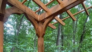 Eine Pergola aus Holz mit einem roten Stuhl und einem Feuerkorb.