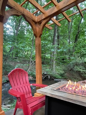 Eine Pergola aus Holz mit einem roten Stuhl und einem Feuerkorb.