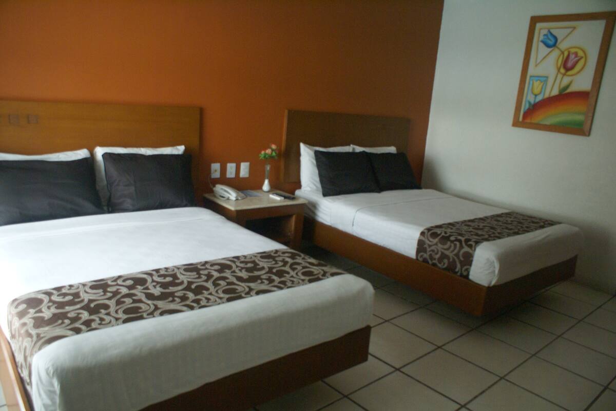 A hotel room with two beds, a nightstand, a phone, and a painting on the wall.