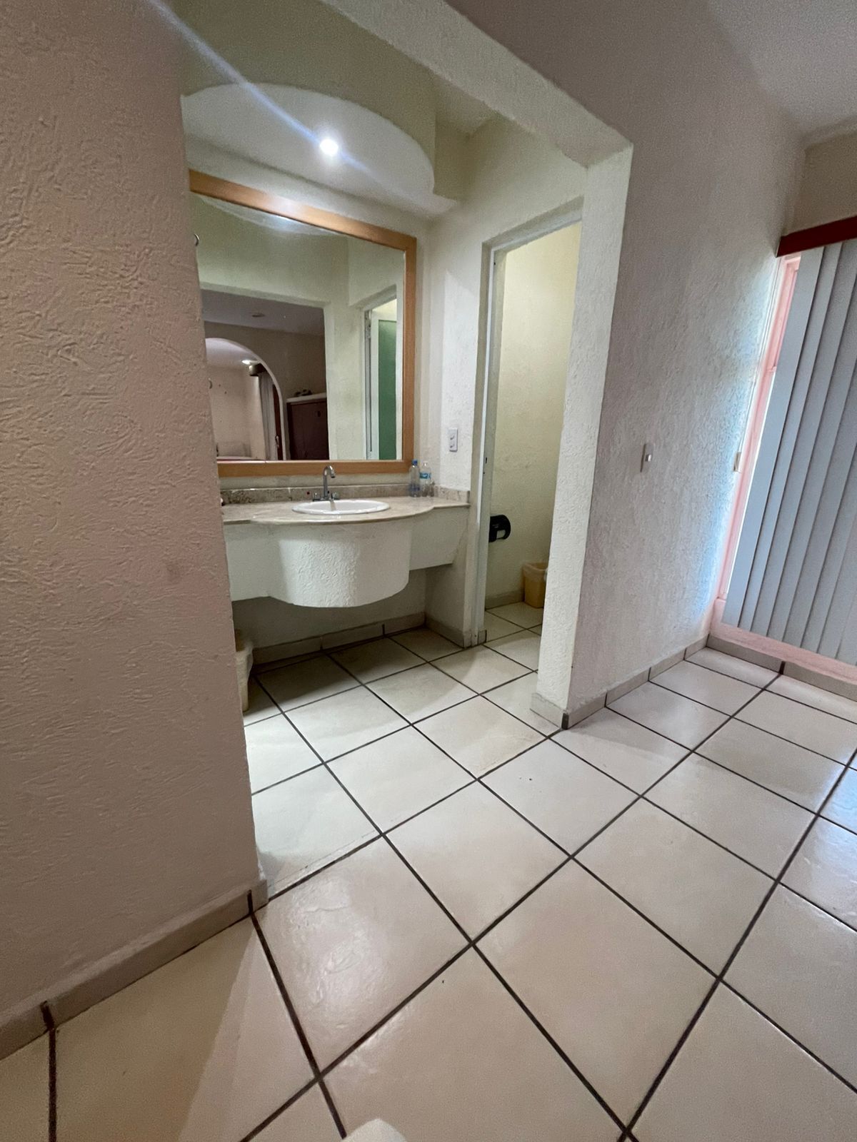 A bathroom with a sink, mirror, and tiled floor.