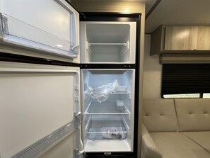 Compact living space with a double-door refrigerator and comfortable seating area.